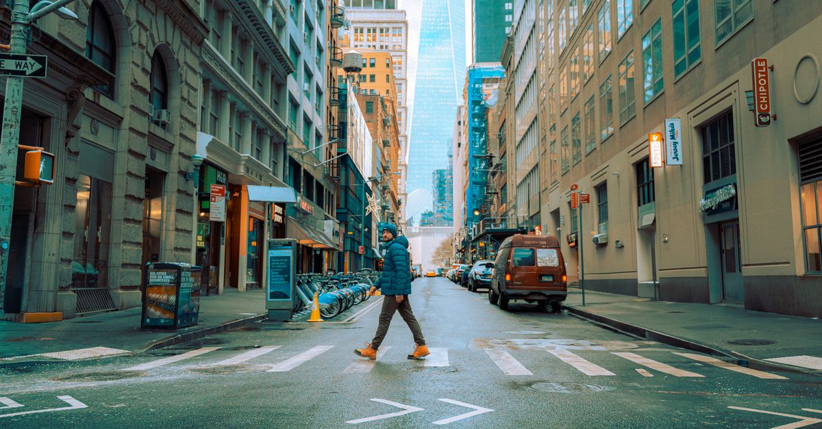 A person crosses a street in downtown Manhattan, New York during winter.