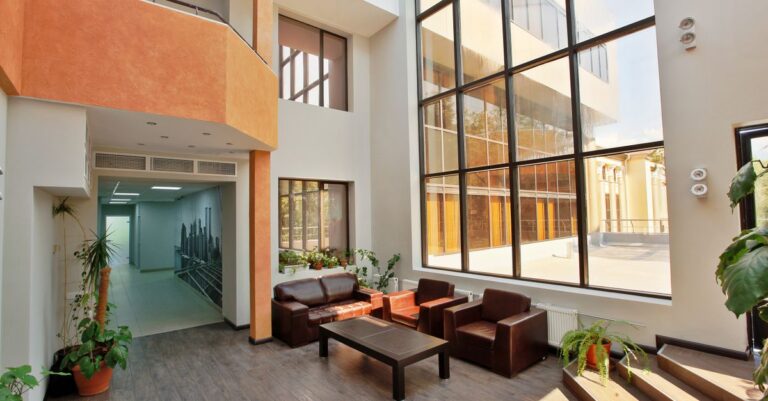 A spacious, modern lobby with high ceilings, large windows, and contemporary furniture.