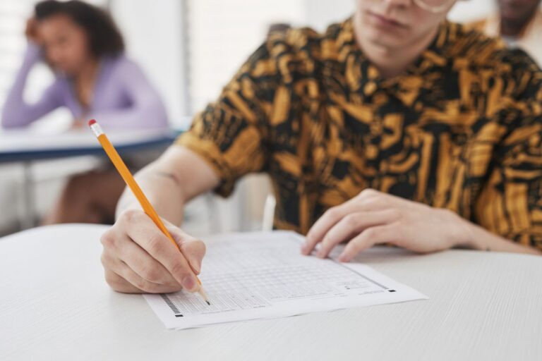 Adult test-taker filling in an exam answer sheet with a pencil