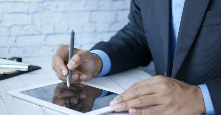 Man in suit using stylus on tablet for business work indoors